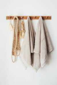 Minimalist bathroom decor with towels and eco-friendly accessories on a wooden rack.